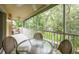 View of the outdoor screened-in balcony with ceiling fan and wicker furniture overlooking the green landscape at 7137 Cedar Hollow Cir, Bradenton, FL 34203