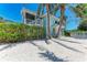 Side view of a two-story beach home with a screen porch and white fence at 733 Holly Rd, Anna Maria, FL 34216