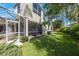 A view of the backyard with a well maintained lawn and a screened in patio, surrounded by trees at 7615 Charleston St, Bradenton, FL 34201