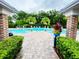 Community pool featuring lounge chairs, palm trees, lush landscaping, and a spacious brick-paved pool deck for residents' enjoyment at 7615 Charleston St, Bradenton, FL 34201