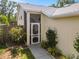 Close-up of the front entrance with a screened door, complemented by colorful flowers and lush greenery at 7716 Geneva Ln, Sarasota, FL 34243
