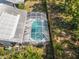 Aerial view of a screened-in pool with clear turquoise water, set within a well-maintained backyard and lush landscaping at 7716 Geneva Ln, Sarasota, FL 34243