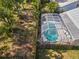 An aerial view showcases a screened-in pool surrounded by lush foliage and a fenced yard, perfect for outdoor enjoyment at 7716 Geneva Ln, Sarasota, FL 34243