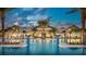 Resort-style community pool with palm trees, lounge chairs, and a grand clubhouse in the background at 7758 Summerland Cv, Bradenton, FL 34202