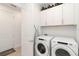 Well-organized laundry room with washer, dryer, white cabinets, and a wine rack at 7758 Summerland Cv, Bradenton, FL 34202
