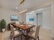 Dining room with wooden table, six chairs, modern chandelier, and beach-themed artwork at 918 Fernleaf Run, Bradenton, FL 34212