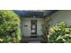 A home's inviting entrance with a secure door, framed by lush greenery on either side adding privacy and curb appeal at 120 Sw Monroe N Cir, St Petersburg, FL 33703