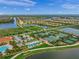 An aerial view shows multiple tennis courts and a pool surrounded by homes and water in the IslandWalk Community at 13391 Dimarco St, Venice, FL 34293