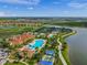 Aerial view of community clubhouse, pool, tennis courts, and adjacent lake at 13391 Dimarco St, Venice, FL 34293