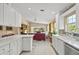 Well-lit kitchen with white cabinets, tile countertops, and an open view into the living room and outdoor pool area at 13391 Dimarco St, Venice, FL 34293