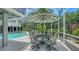 Screened-in patio with a dining table set and an in-ground pool surrounded by lush greenery at 1627 Peregrine Point Ct, Sarasota, FL 34231