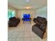 Spacious living room is furnished with reclining sofas, tile floors, and a modern glass coffee table at 1646 Pierpoint St, North Port, FL 34288