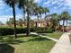 Condominium exterior with a lush green lawn, sidewalk, multiple palm trees, and a bench at 1959 Toucan Way # 206, Sarasota, FL 34232