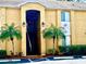 Inviting two-story condo with mature palm trees, dark metal gate, and an assigned parking space in front at 1959 Toucan Way # 206, Sarasota, FL 34232
