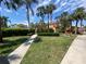 Condominium exterior with a lush green lawn, sidewalk, multiple palm trees, and a bench at 1959 Toucan Way # 206, Sarasota, FL 34232
