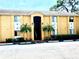 Inviting two-story condo with mature palm trees, dark metal gate, and an assigned parking space in front at 1959 Toucan Way # 206, Sarasota, FL 34232