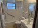 Bright bathroom with shower-tub combo, white tile, and neutral wallpaper at 211 55Th Nw St, Bradenton, FL 34209