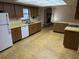 Retro style kitchen featuring laminate countertops, white appliances, and a view of the fireplace at 211 55Th Nw St, Bradenton, FL 34209