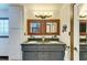 Elegant bathroom with dual sinks, granite countertops, framed mirrors and linen closet for storage at 2321 Milford Cir, Sarasota, FL 34239