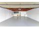 An inside view of the garage showcasing exposed ceiling trusses, painted walls, and a smooth gray concrete floor at 2321 Milford Cir, Sarasota, FL 34239