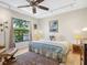 Comfortable bedroom with tile floors, a ceiling fan, and a large window overlooking the lush backyard at 3900 Country View Dr, Sarasota, FL 34233