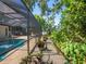 A screened-in lanai area offers a view of the beautiful pool and tropical landscaping at 3900 Country View Dr, Sarasota, FL 34233