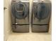 Modern front load washer and dryer set with gray finish, matching storage drawers, and tile flooring at 4428 Conchfish Ln, Osprey, FL 34229