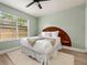A pretty bedroom features a bed with white linens and a wooden headboard, ceiling fan, and a window at 522 31St W St, Bradenton, FL 34205