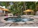 A backyard stone pool with a waterfall feature, surrounded by lush landscaping and seating areas at 522 31St W St, Bradenton, FL 34205