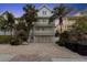 Three-story beach house with balconies, a two-car garage, and lush tropical landscaping at 538 Canal Rd, Sarasota, FL 34242
