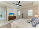 Bright, contemporary bedroom with tray ceiling, ceiling fan, and rustic wood dresser with flatscreen TV at 5428 Title Row Dr, Bradenton, FL 34210