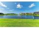 Beautiful view of a serene pond with a fountain, lined with green grass and homes at 5428 Title Row Dr, Bradenton, FL 34210
