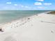 Vast aerial view of a serene beach featuring white sand, calm waters, and scattered beachgoers at 5569 Cape Leyte Dr, Sarasota, FL 34242