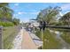 Well-maintained boat dock with a boat lift on a scenic canal, surrounded by lush landscaping and sunny skies at 5569 Cape Leyte Dr, Sarasota, FL 34242