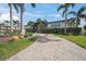 Charming single-story home with lush landscaping, a gray garage door, and a spacious circular brick driveway at 5569 Cape Leyte Dr, Sarasota, FL 34242