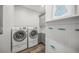 Bright laundry room featuring a modern washer and dryer set, storage cabinets, and nautical-themed decor at 5569 Cape Leyte Dr, Sarasota, FL 34242