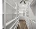 Spacious walk-in closet featuring custom shelving and drawers for optimal organization and hardwood floors at 5569 Cape Leyte Dr, Sarasota, FL 34242
