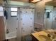 This bathroom features a tub with shower curtain, decorative tile, vanity with sink, and large mirror at 620 Camellia Ave, Ellenton, FL 34222