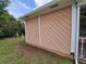 Exterior view featuring the peach-colored wall of the home, adjacent to green space at 6305 Bikini Rd, Sarasota, FL 34241