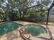 Relaxing screened-in pool and spa with lush greenery creates a serene outdoor oasis at 6305 Bikini Rd, Sarasota, FL 34241