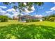 A house backyard with an enclosed pool, blue skies, and manicured lawn at 7133 Dornough Ln, Bradenton, FL 34202