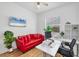 Bright home office featuring a red couch, modern desk, and natural light at 7133 Dornough Ln, Bradenton, FL 34202