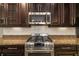 Up-close view of a stainless steel gas range and microwave, set against dark cabinets and granite countertops at 773 Rosemary Cir, Bradenton, FL 34212