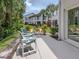 A patio with seating, overlooking tropical landscaping and nearby buildings at 821 Montrose Dr # 103, Venice, FL 34293