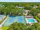 An aerial view of neighborhood tennis courts, pool, and surrounded by mature trees and residential homes at 8240 Cypress Lake Dr, Sarasota, FL 34243