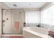 Bright bathroom featuring a soaking tub, glass-enclosed shower, and large window at 8240 Cypress Lake Dr, Sarasota, FL 34243