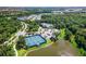 An aerial view of community tennis courts, pool, clubhouse and nearby houses and roads with plenty of trees and greenery at 12261 Stuart Dr, Venice, FL 34293