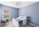 Blue bedroom featuring ceiling fan, large window, and stylish decor at 12261 Stuart Dr, Venice, FL 34293