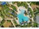 Overhead view of community pool showcasing its unique shape, water slide, lounge areas, and lush landscaping at 12261 Stuart Dr, Venice, FL 34293