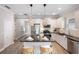Modern white kitchen featuring an island with bar seating, stainless steel appliances, and stylish pendant lighting at 12261 Stuart Dr, Venice, FL 34293